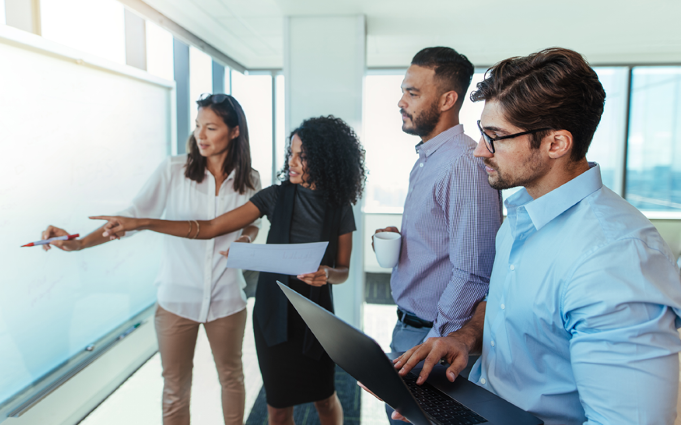 Group of people discussing near a white board